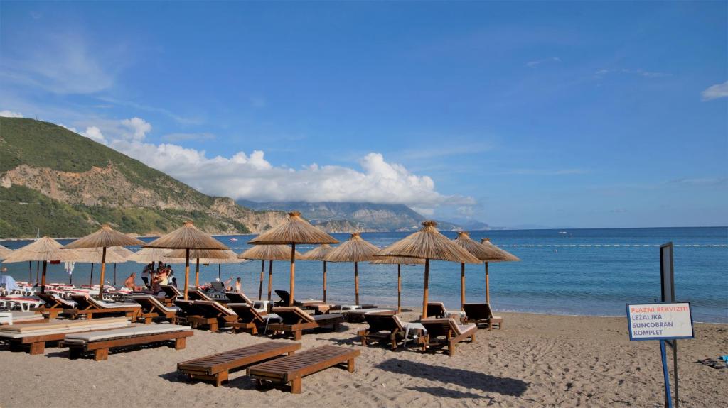 布德瓦MM Apartments的海滩上设有椅子和遮阳伞,还有大海