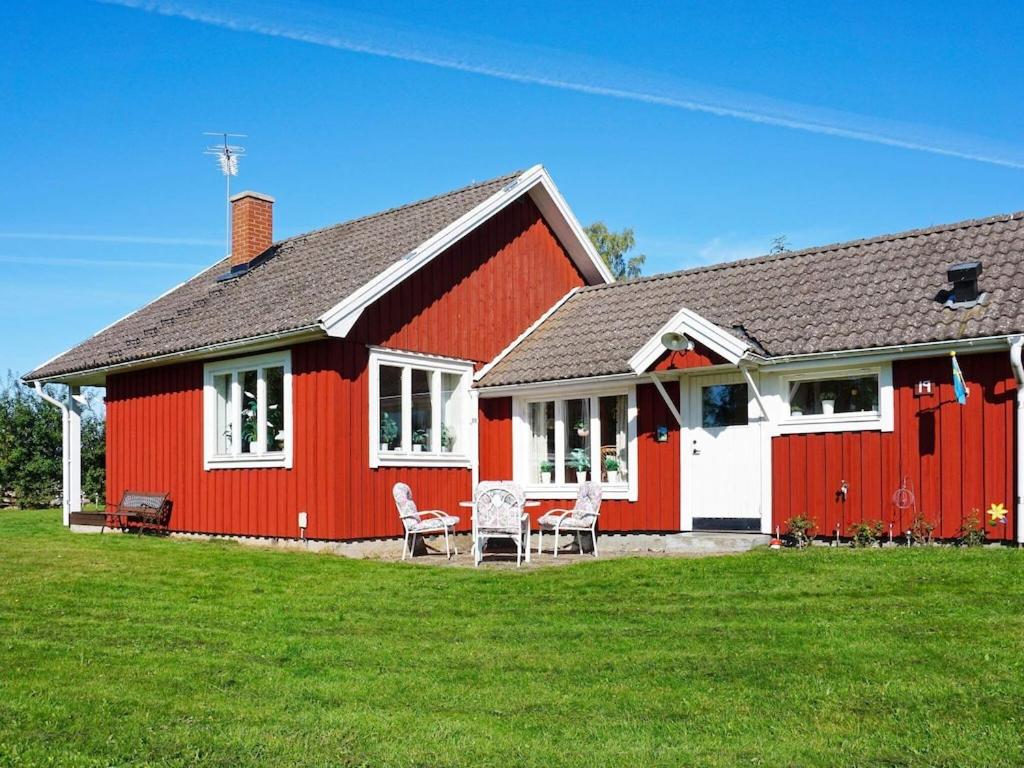 费尔耶斯塔登5 person holiday home in F RJESTADEN的红色的房子,配有两把椅子和一张桌子