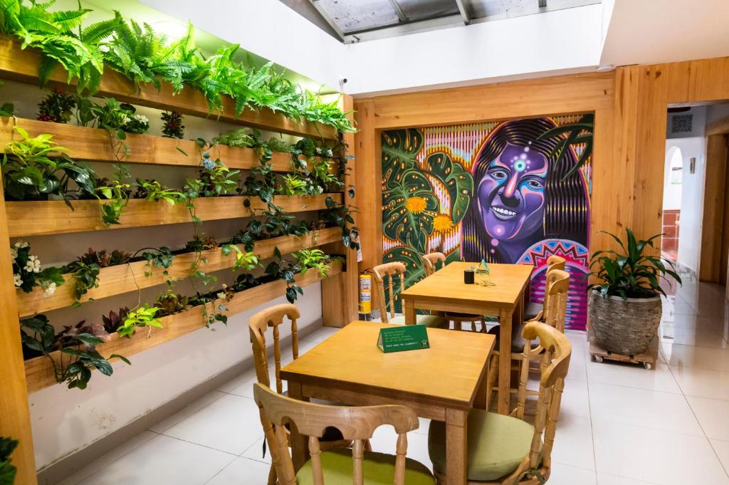 麦德林ADN Algo de Nosotros - Malaika的一间设有两张桌子的餐厅,墙上有植物