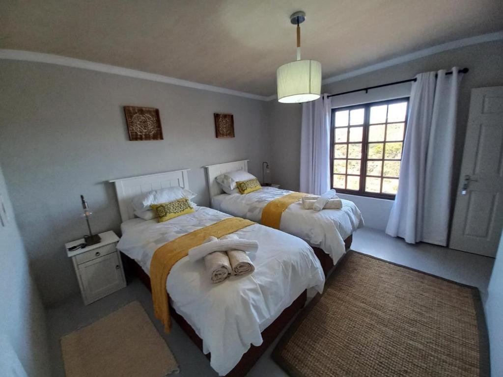 莱迪史密斯Prinspoort Klein Karoo Stay的一间卧室设有两张床和窗户。