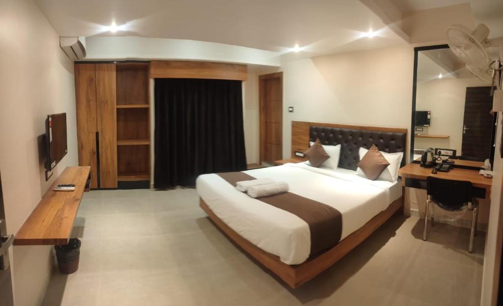古瓦哈提Aditya Inn的一间大卧室,配有一张大床和一张书桌