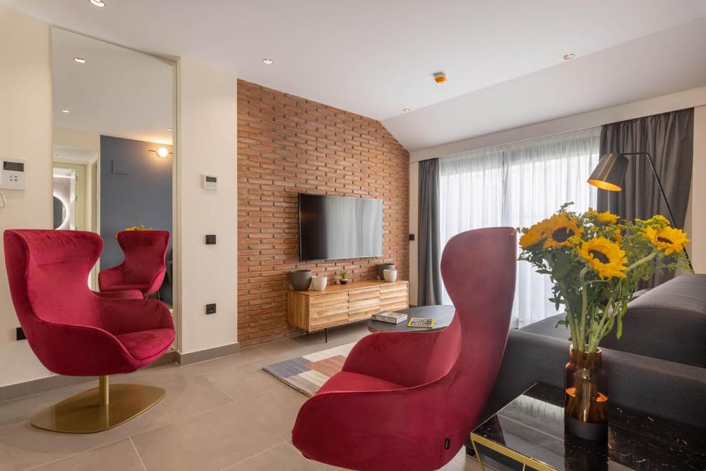 马拉加Home Art Apartments Soho的客厅配有2把红色椅子和电视