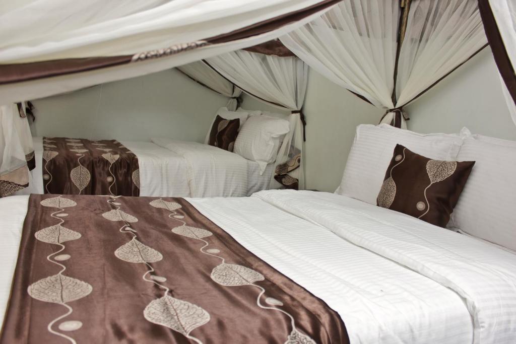 内罗毕哈达萨酒店的一间卧室配有两张带白色和棕色床单的床