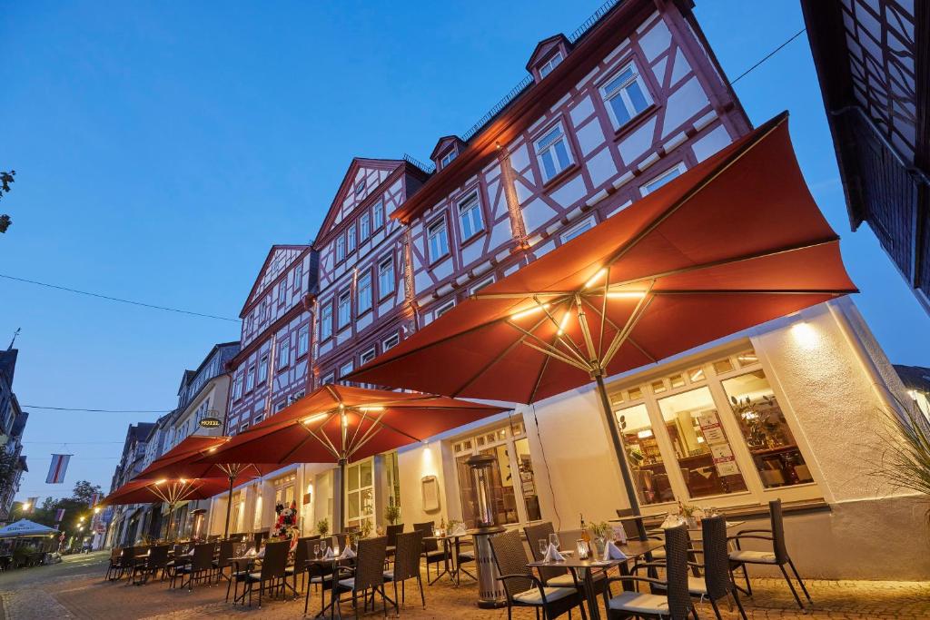 蒙塔鲍尔施勒蒙酒店的大楼前的餐厅,配有桌子和遮阳伞