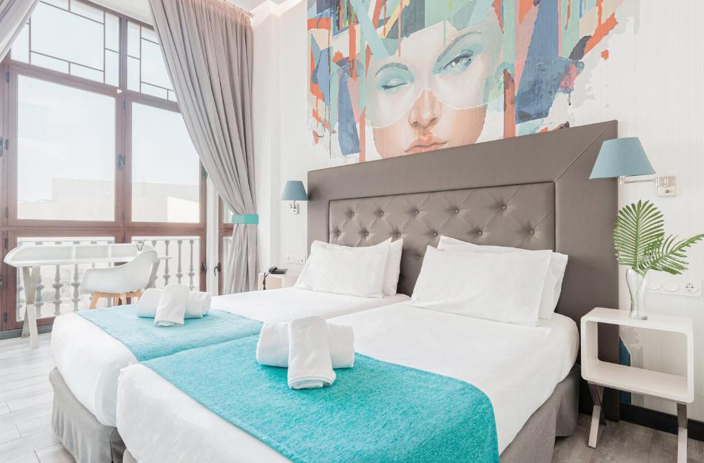 休达Oh Nice Revellin Ceuta的卧室内的两张床,墙上有绘画作品
