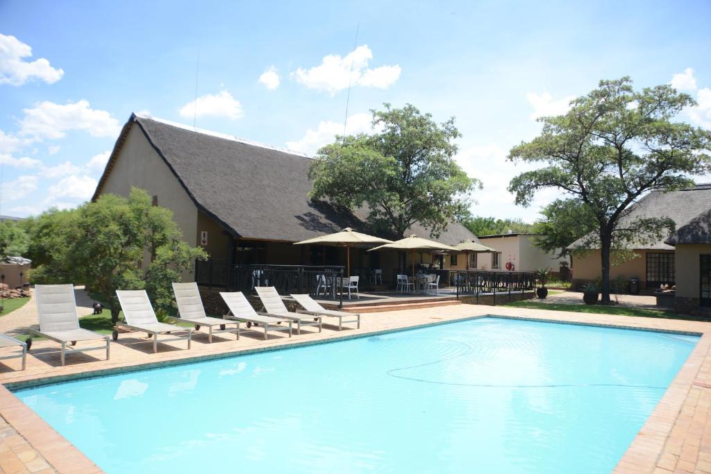 布里茨Ukutula Lion Lodge的一座带躺椅的游泳池和一座建筑