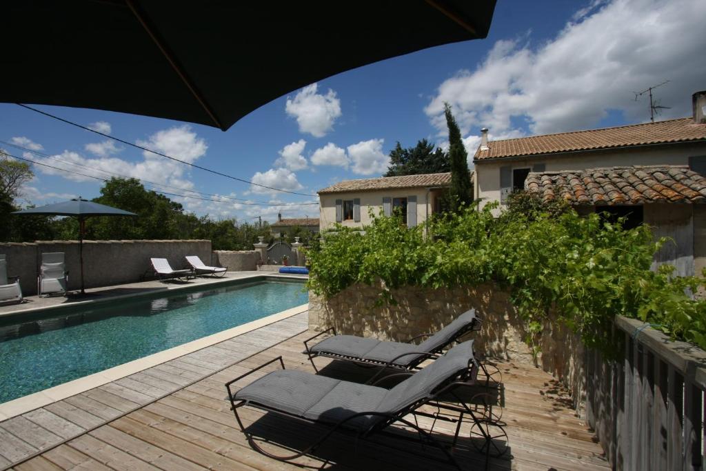 圣雷米普罗旺斯马斯图尔特莱斯旅馆的一个带2把躺椅和遮阳伞的游泳池