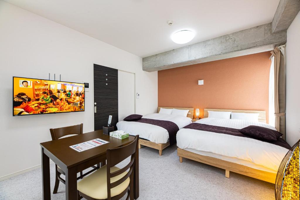 鹿儿岛STAYTUS - Vacation STAY 62199v的酒店客房设有两张床、一张桌子和一张桌子。