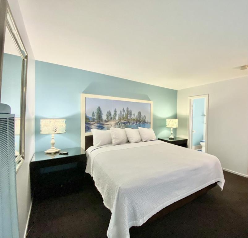 南太浩湖Bluebird Day Inn & Suites的一间卧室配有一张带两盏灯的大型白色床。