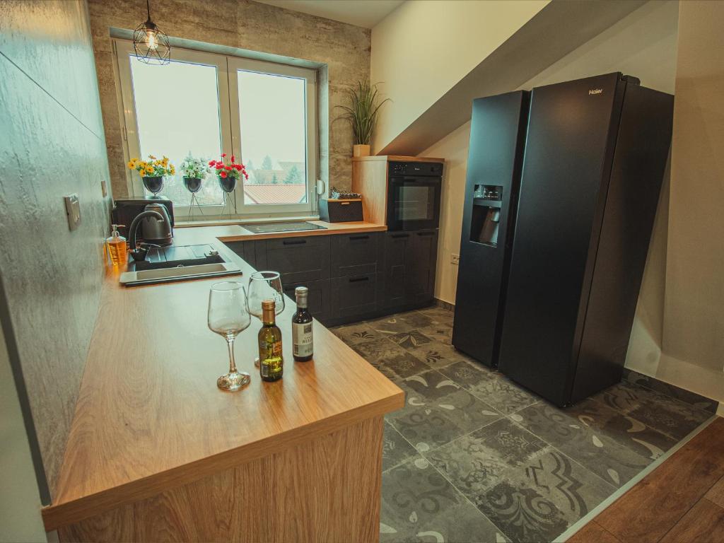 奥西耶克APARTMANI INFINITY的厨房配有黑色冰箱和带酒杯的吧台