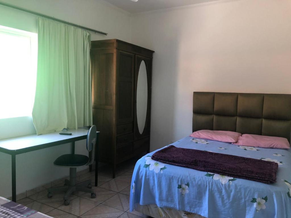 平达莫尼扬加巴Hotel Pousada Liberdade的一间卧室配有一张床、一张桌子和一把椅子