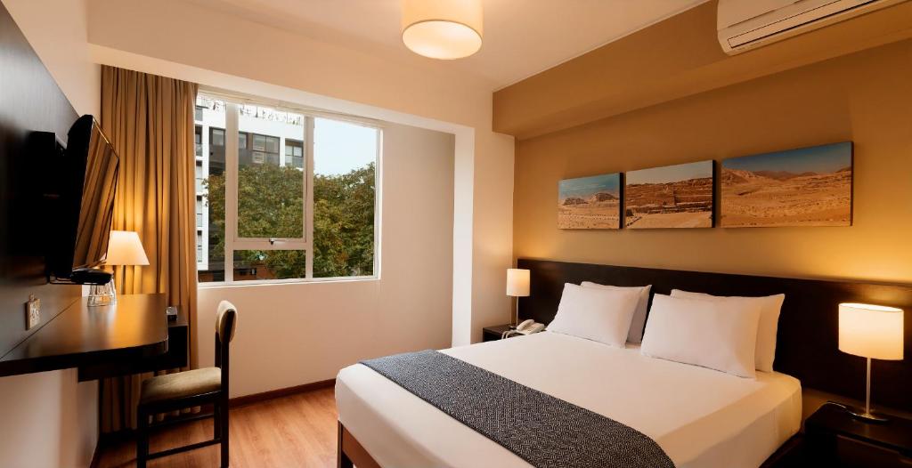 利马向日葵酒店的一间卧室配有一张床、一张书桌和一个窗户。