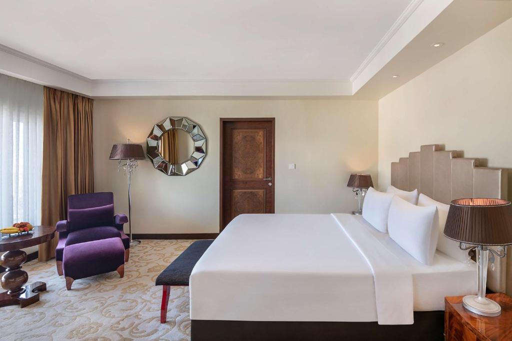 艾哈迈达巴德Radisson Blu Hotel Ahmedabad的卧室配有一张白色大床和紫色椅子