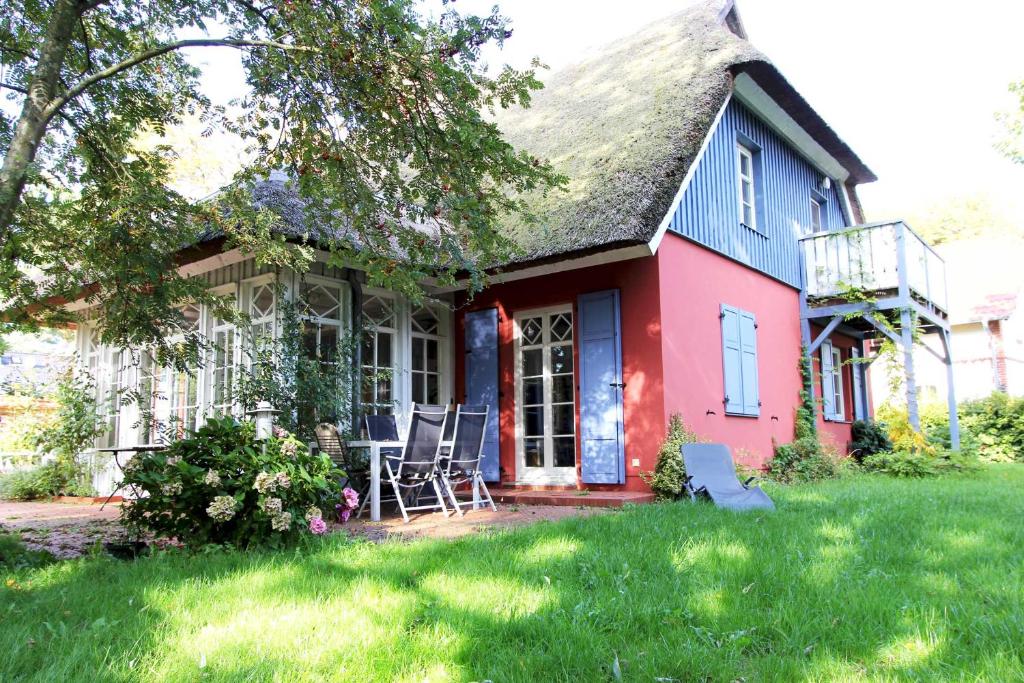普雷罗Darßer Landhaus的院子里的红色和蓝色房子,带椅子