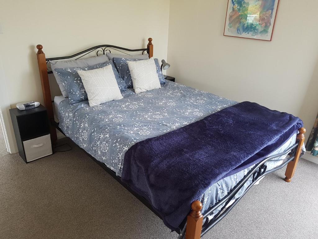 HampdenTui Cottage的一间卧室配有一张带蓝色床单和枕头的床。