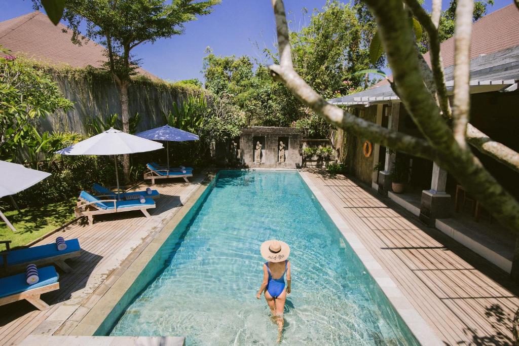 努沙杜瓦La Berceuse Resort and Villa Nusa Dua by Taritiya Collection的戴帽子的女人在游泳池里