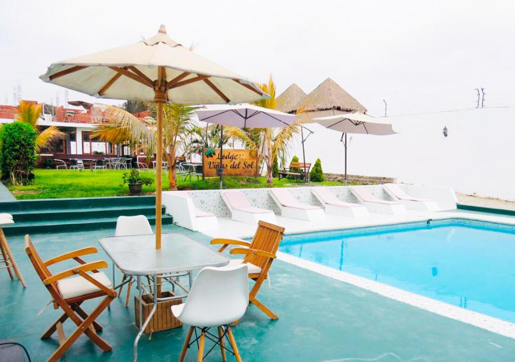 上钦查Hotel Viñas del Sol Eterno的一个带桌椅和遮阳伞的游泳池