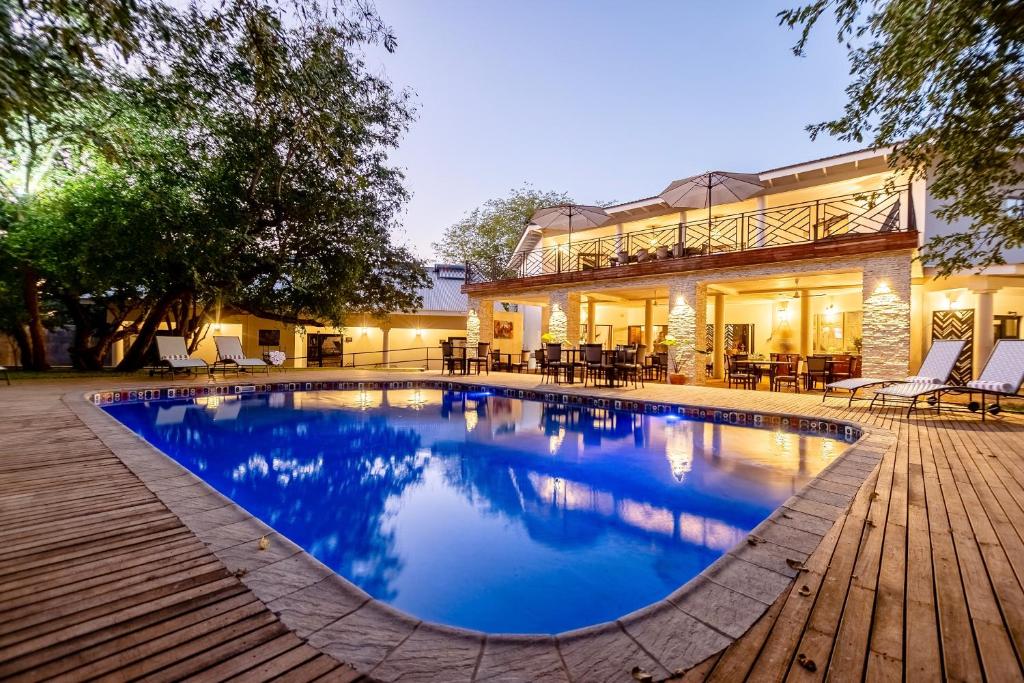 维多利亚瀑布Nkosi Guest Lodge的房屋前的游泳池