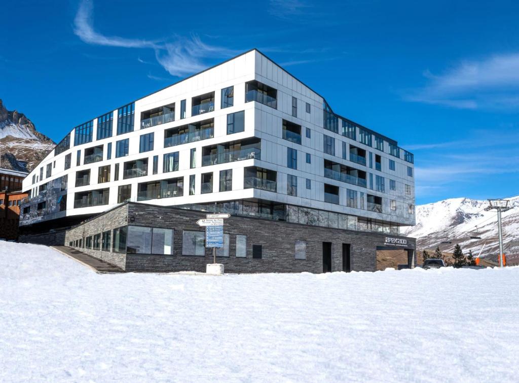 蒂涅Hôtel VoulezVous by Les Etincelles的一座大雪楼,背景是群山