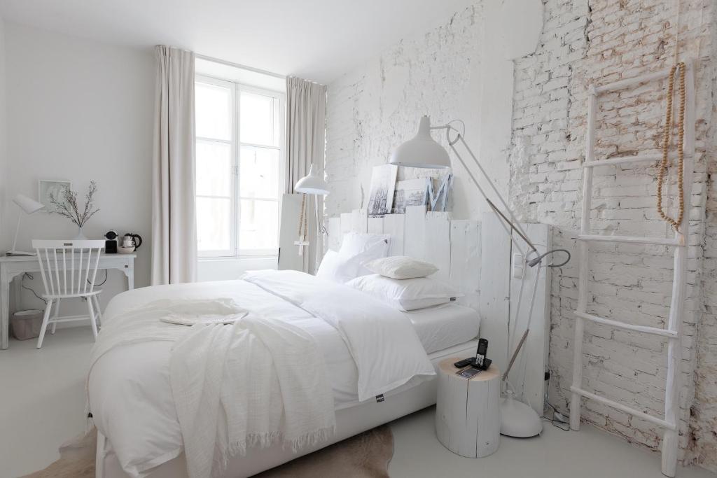 乌得勒支鹅妈妈酒店的白色的卧室,配有床和白色砖墙