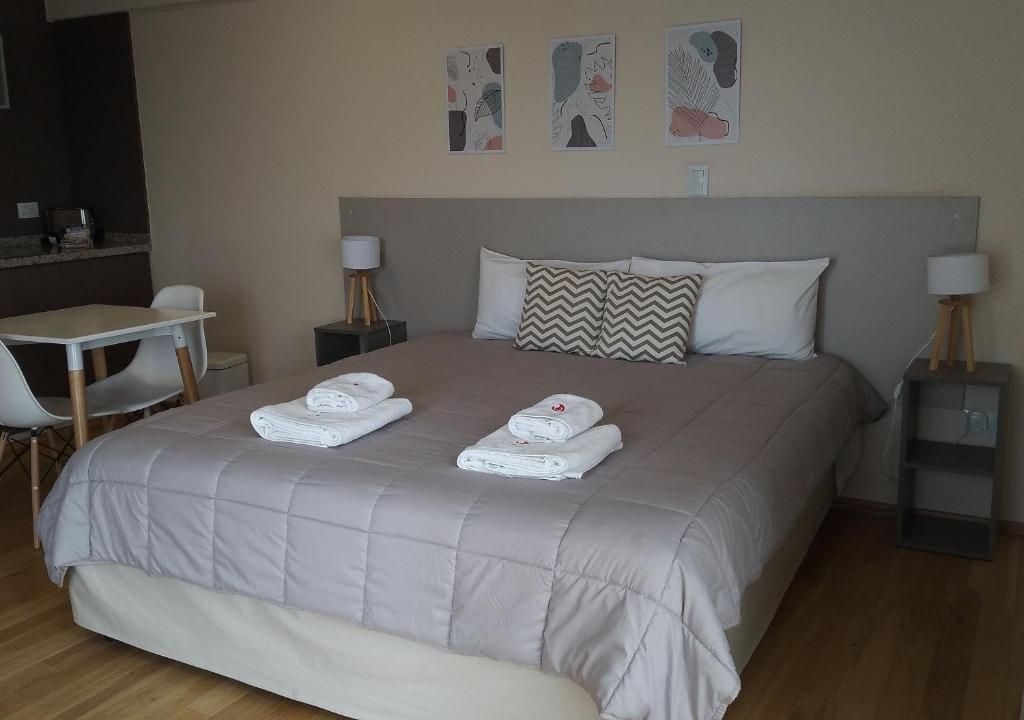 卢汉德库约Apart Hotel Quijote by DOT Suites的一间卧室配有一张床,上面有两条毛巾
