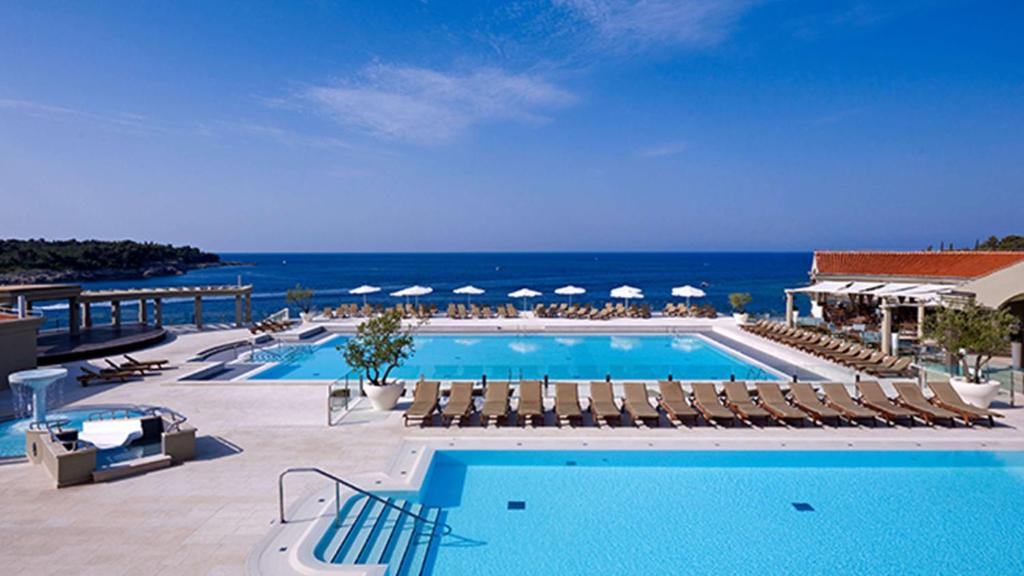 普拉沃迪拉普拉公园广场酒店的一个带椅子的游泳池,背景是大海