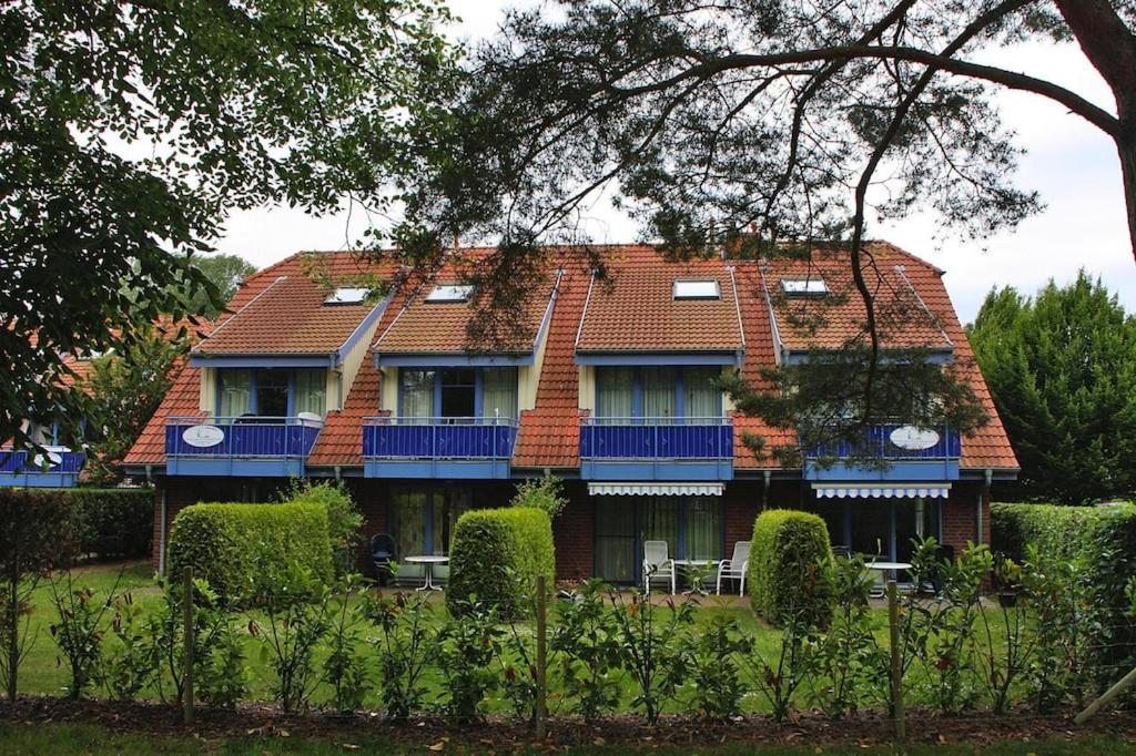 博尔滕哈根Apartment in the Papillon holiday village, Boltenhagen的一座带红色屋顶和蓝色阳台的房子