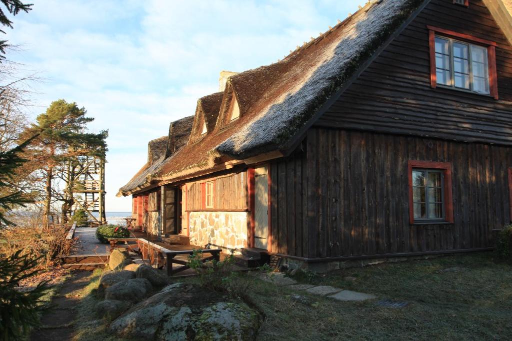 HaeskaTuulingu Guest House at Matsalu National Park的茅草屋顶的房子,外面设有长凳