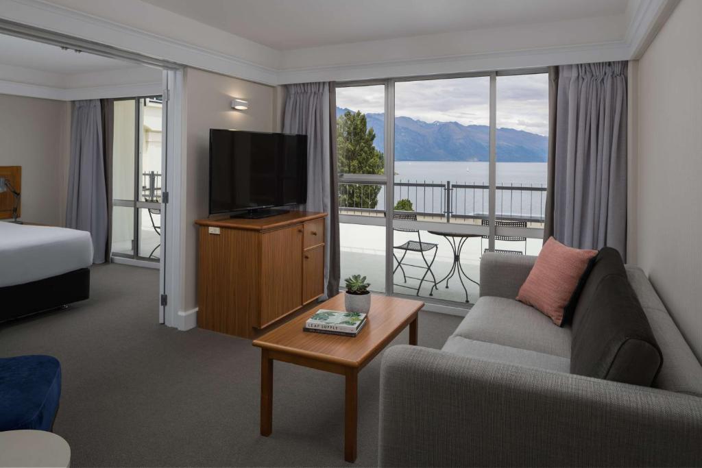 皇后镇Rydges Lakeland Resort Queenstown的酒店客房设有沙发、电视和阳台。