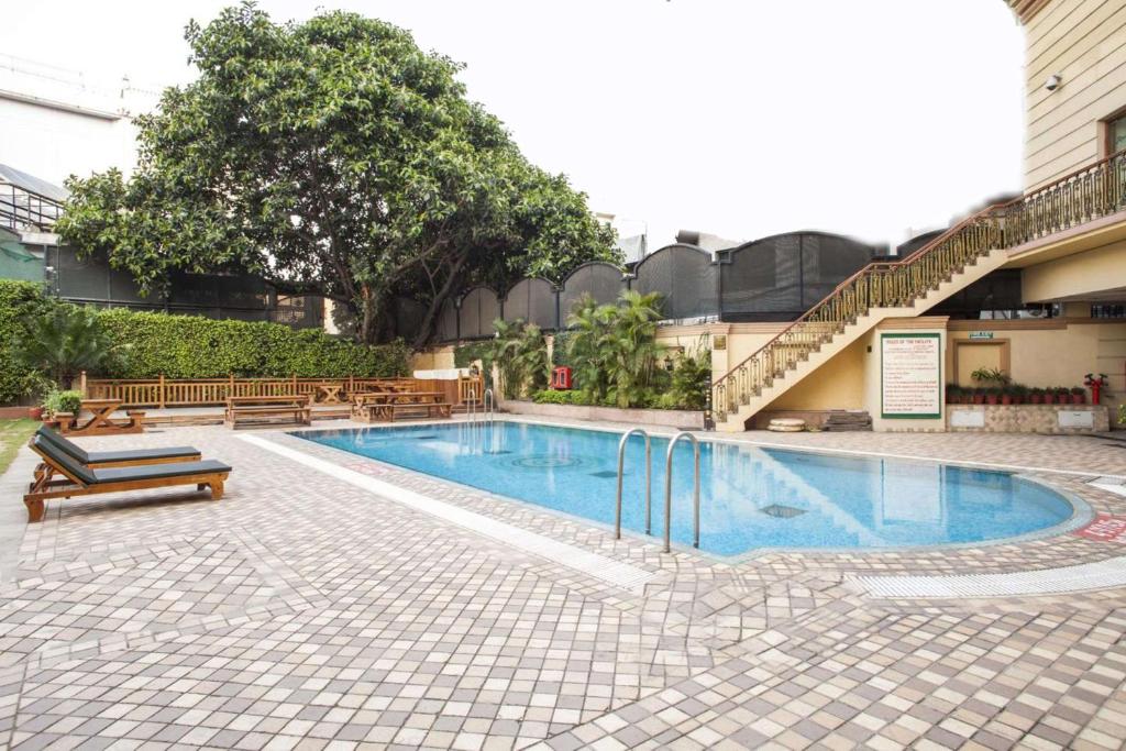 贾朗达尔贾朗达尔丽筠酒店的一座带长椅的游泳池,位于大楼旁