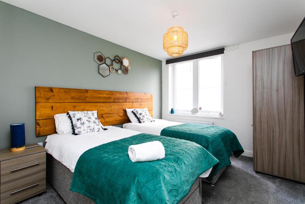 泰恩河畔纽卡斯尔Portland Apartments 198 by #ShortStaysAway的一间卧室配有两张带绿色和白色床单的床