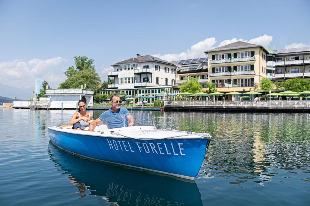 米尔施塔特SEEGLÜCK Hotel Forelle Superior的坐在蓝色小船上的男人和女人