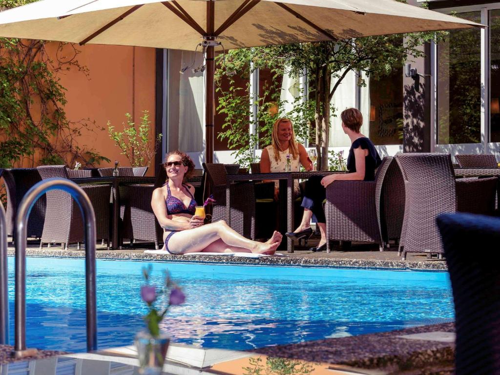 柏林柏林市西美居酒店的一群人坐在游泳池周围
