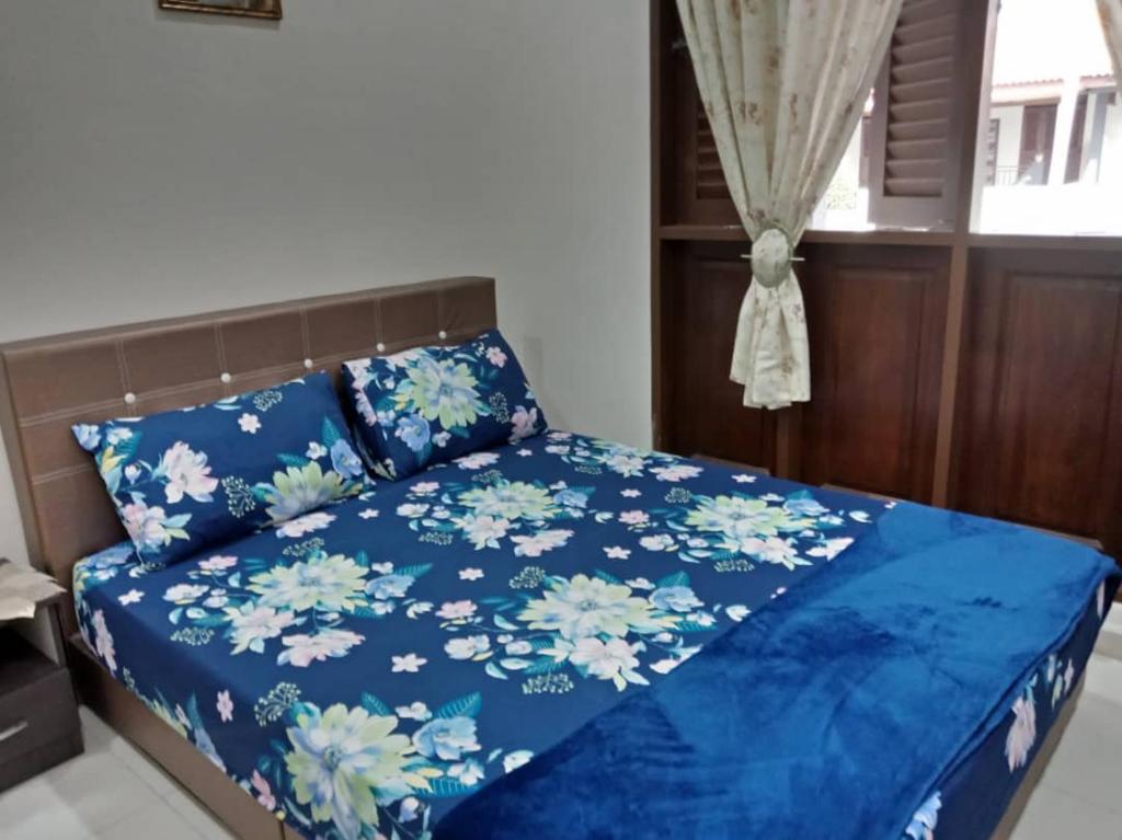 马六甲Rumah Melaka的一间卧室配有一张带鲜花的蓝色床
