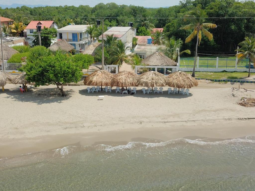 科韦尼亚斯Hotel Cabaña Playa DanRay的沙滩上带椅子和草伞的海滩