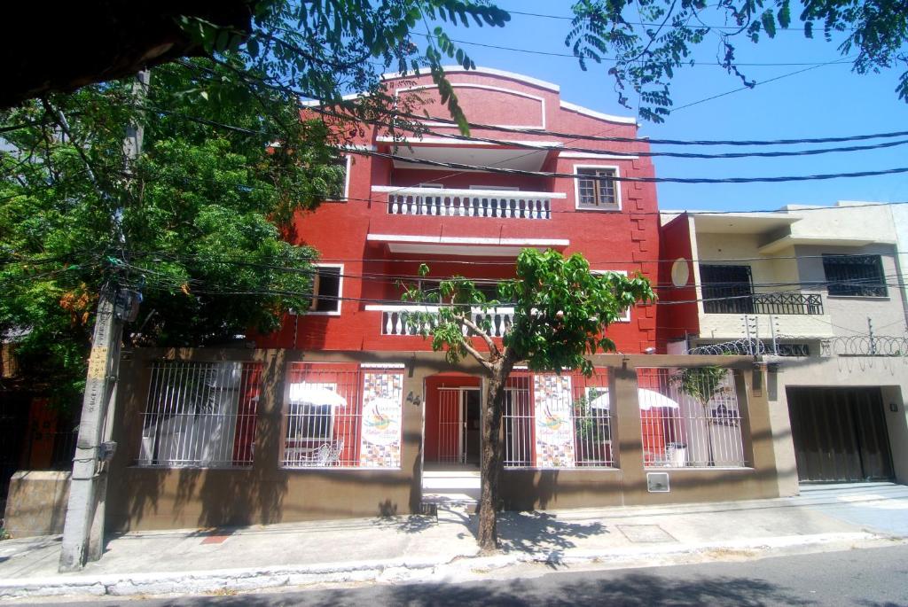 福塔莱萨Refúgio Pousada Fortaleza的前面有棵树的红色建筑