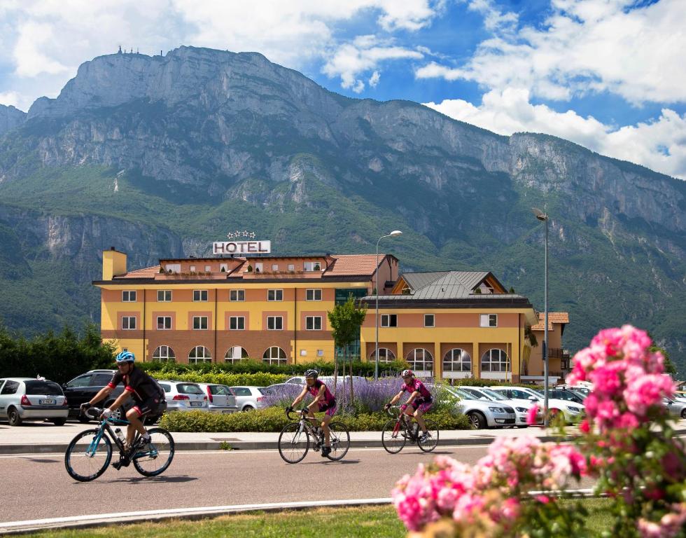特伦托萨托利酒店的三人骑着自行车沿着建筑前的一条道路行驶
