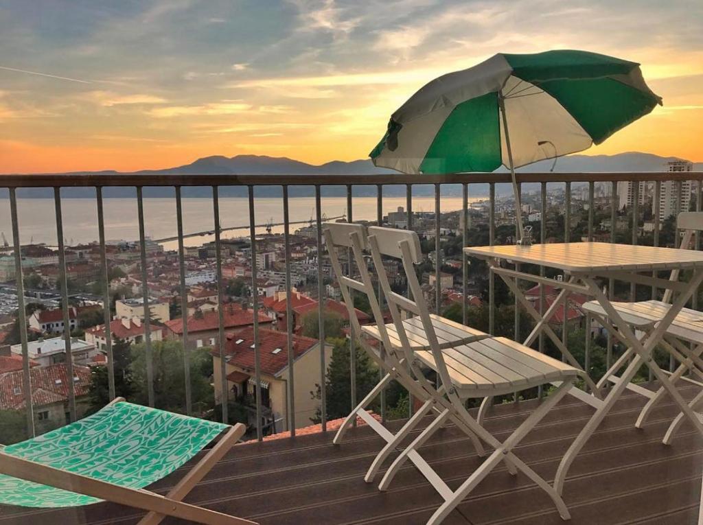 里耶卡Linden Trsat with balcony的阳台配有一张桌子和两把椅子以及一把遮阳伞。