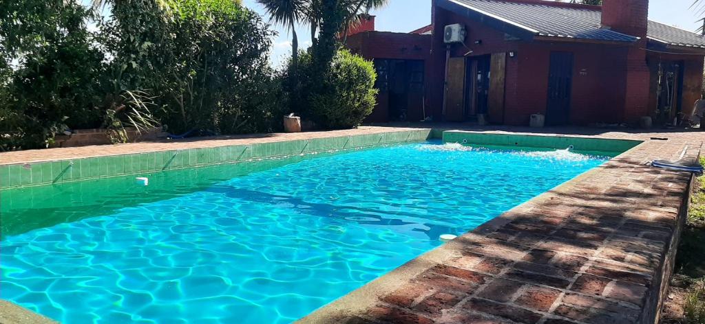 马德普拉塔Casa con piscina en Sierra de los Padres的一座房子前面的蓝色海水游泳池