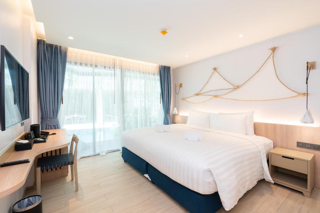 攀瓦海滩Panwaburi Beachfront Resort - SHA Extra Plus的酒店客房设有一张大床和一张书桌。