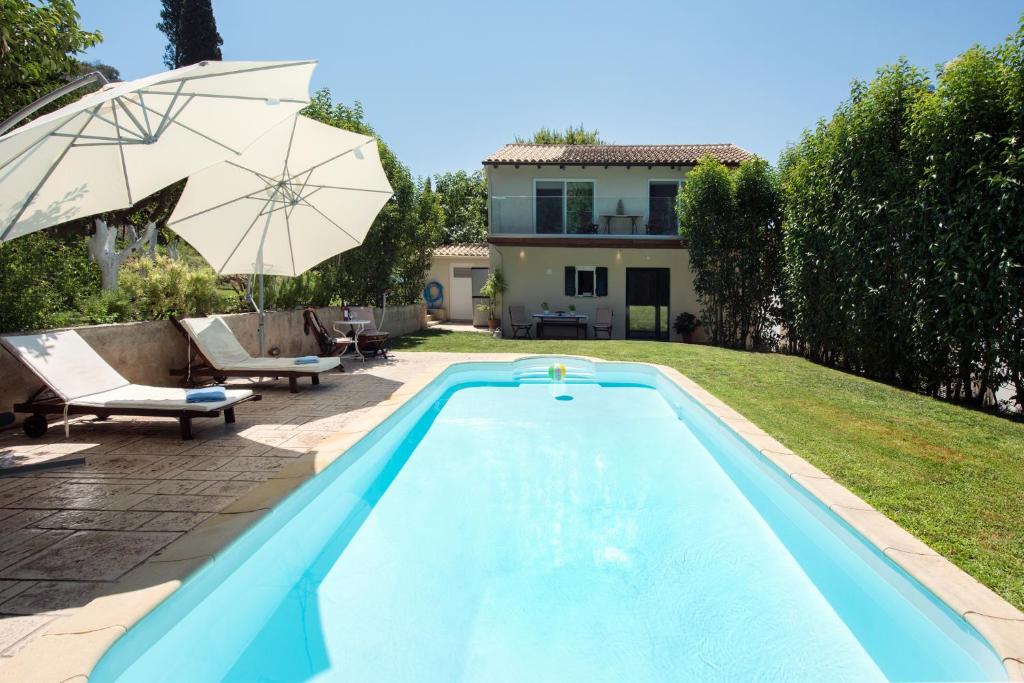 科孚镇Spitaki Pool House的一个带遮阳伞和房子的游泳池