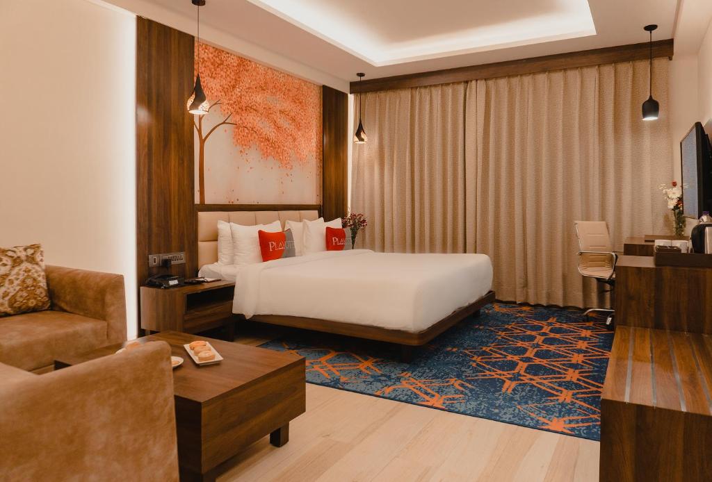 印多尔Playotel Premier Vijay Nagar的酒店客房配有一张床、一张书桌和一张沙发。