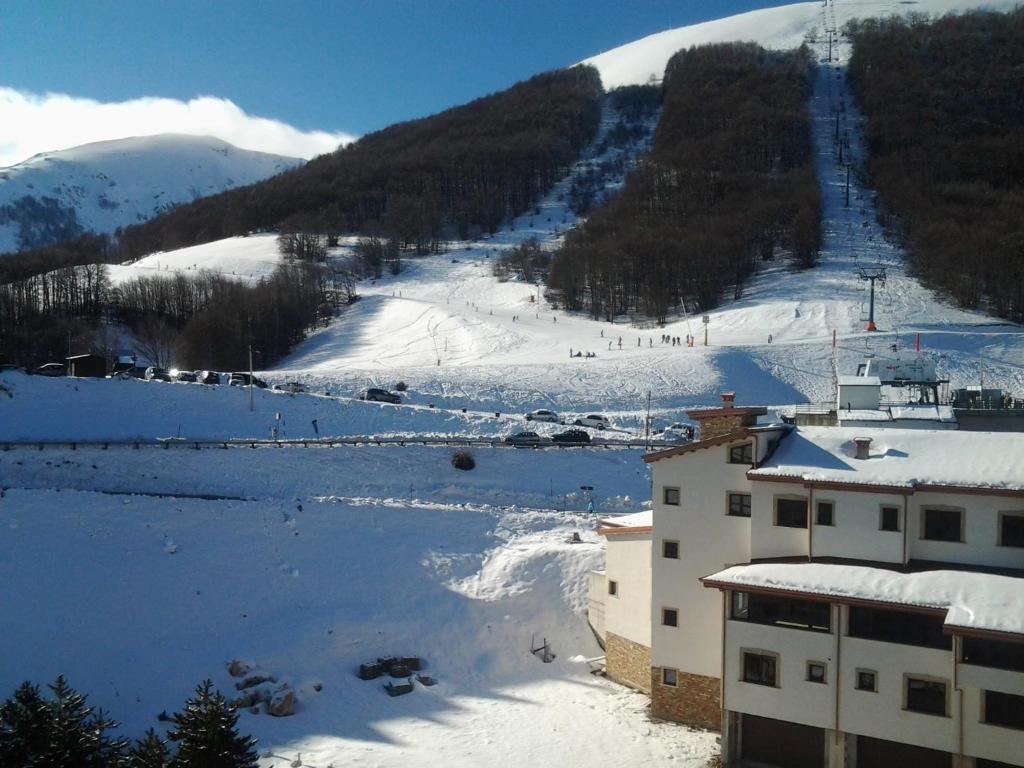 罗卡拉索Monolocale Residence Paradiso Aremogna a due passi dagli impianti sciistici的一座雪覆盖的山,有滑雪场和一座建筑