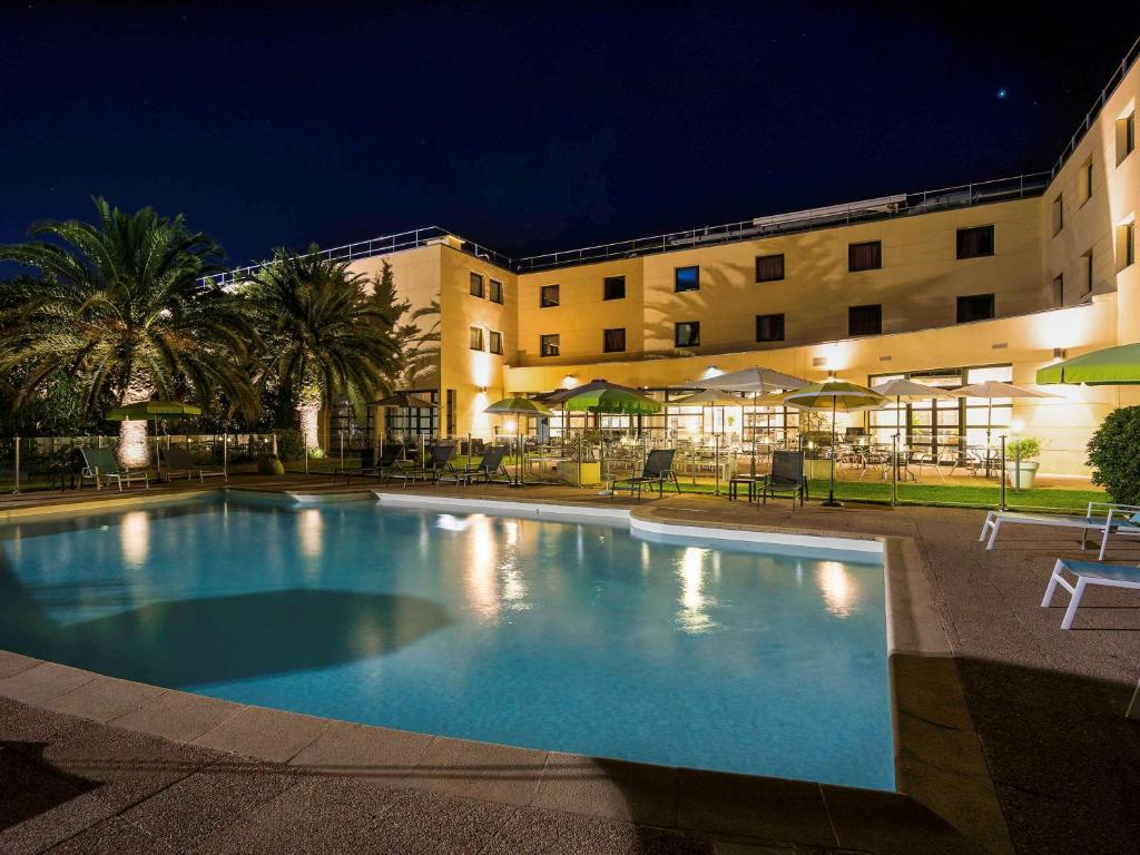 戛纳戛纳曼德里尔美居酒店的夜间在酒店前的游泳池