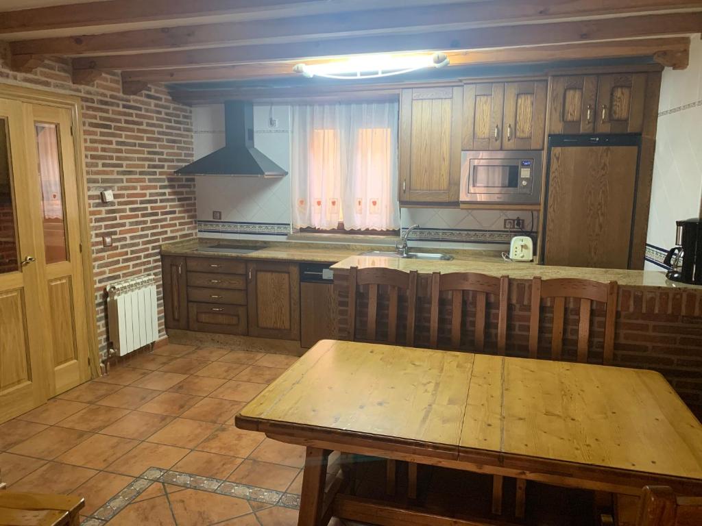 La HorcajadaCasa Rural Los Tasajos的厨房配有木制橱柜和木桌。