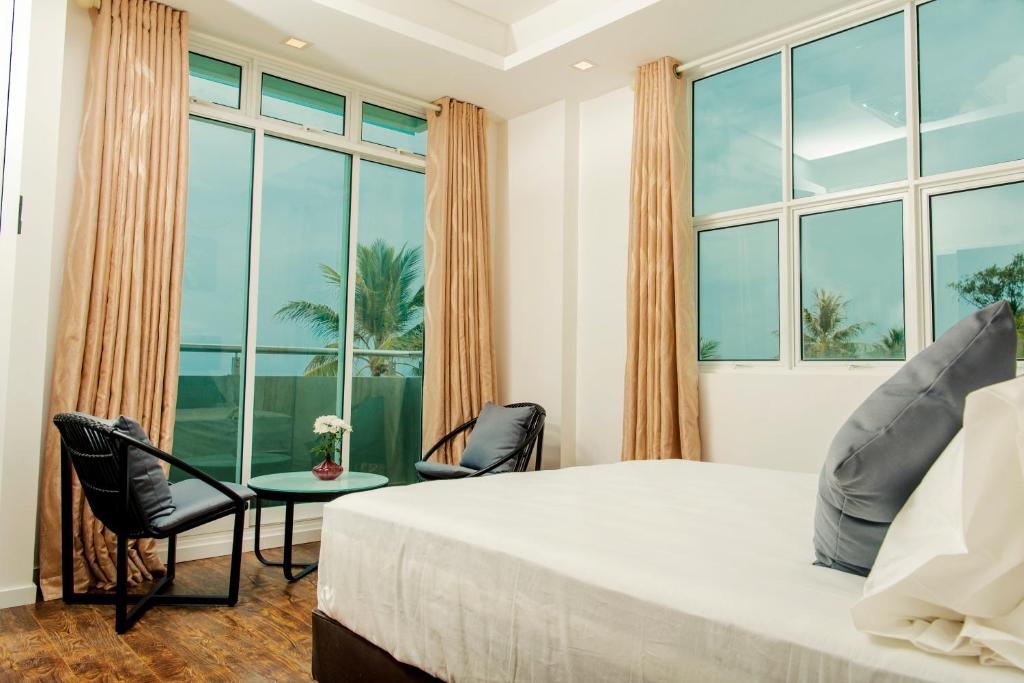 胡鲁马累Acacia Beach Hotel的一间卧室设有一张大床、椅子和窗户。