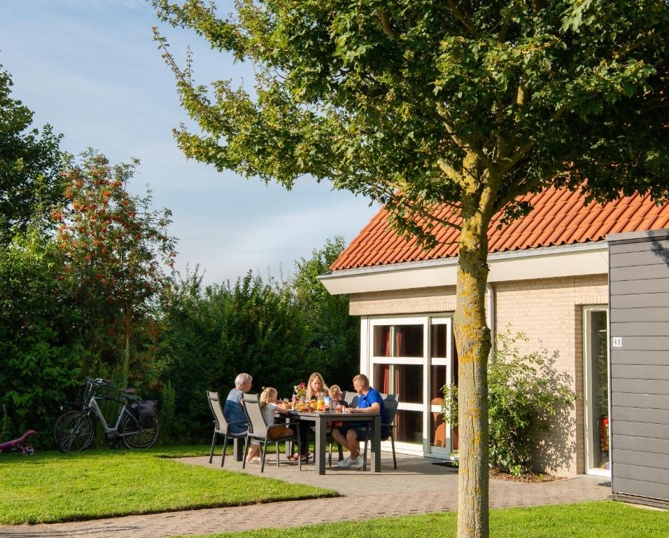 柯德科克Vakantiepark Broedershoek的一群人坐在花园里的桌子旁