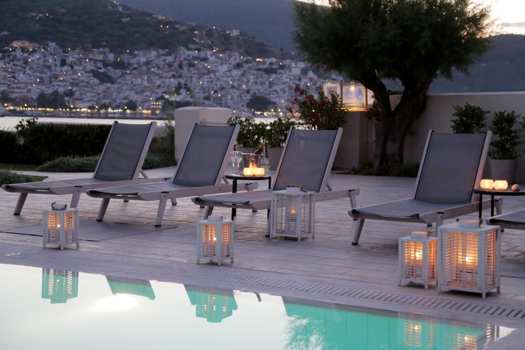 斯科派洛斯Skopelos Village Hotel的一组椅子坐在游泳池旁