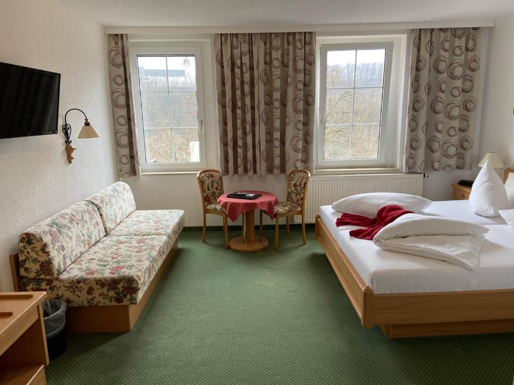 LunzenauDas Muldenschlösschen - Gästehaus & Restaurant的酒店客房,设有两张床和一张沙发