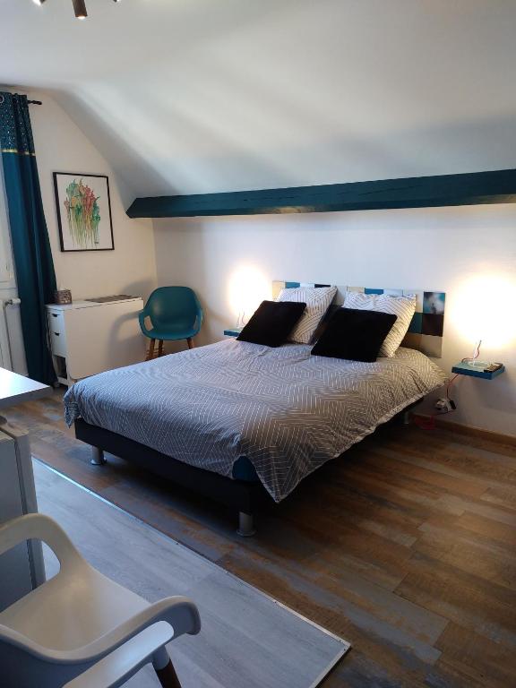 Saint-Germain-du-CorbéisStudio et chambres d'hôtes les nuits de Gesnes的一间卧室配有一张大床和一张绿色椅子